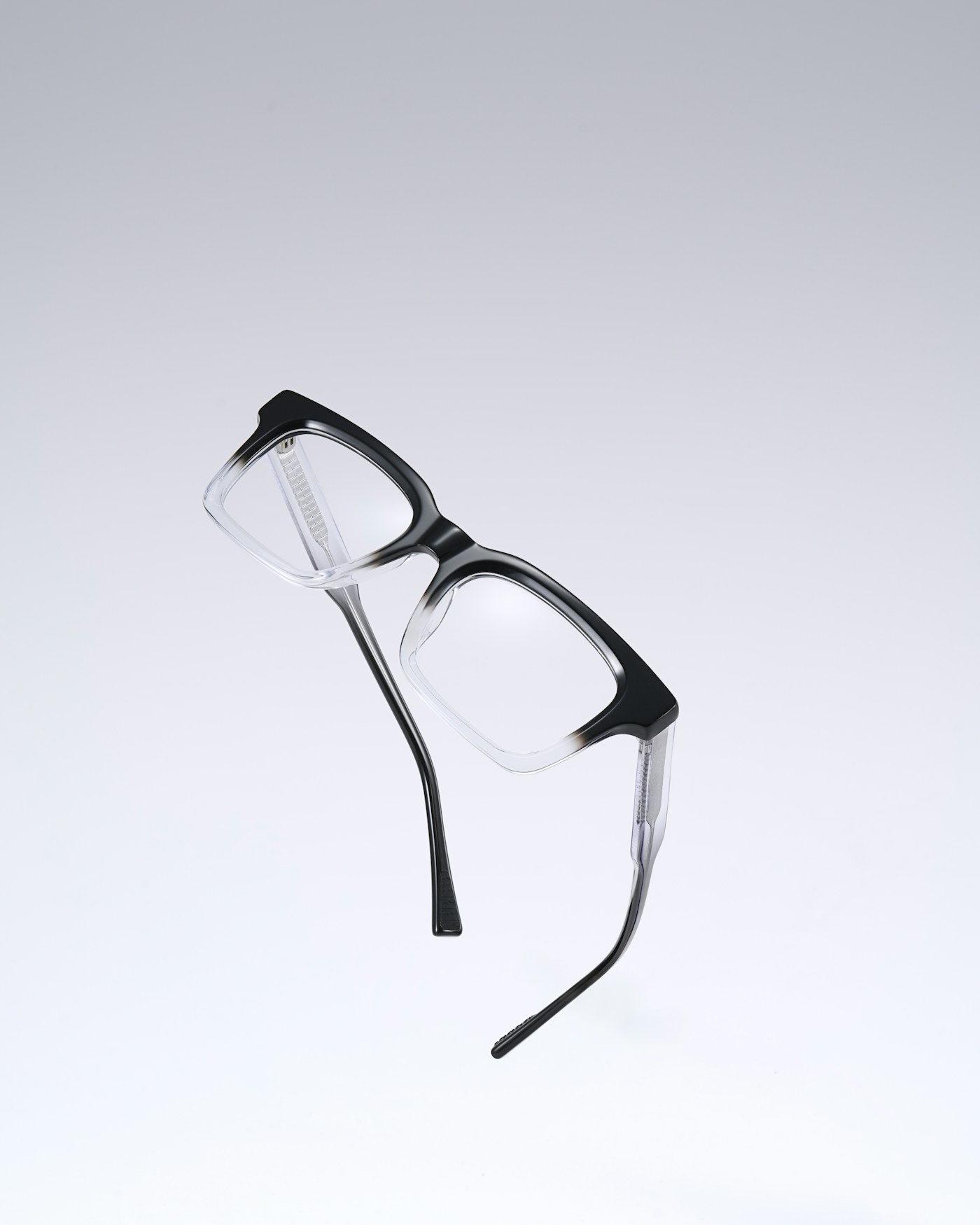 Black and clear eyeglasses floating on a light backdrop